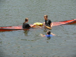 Kristina and Daniel sitting in a sunken canoe. Mom swimming over to help.