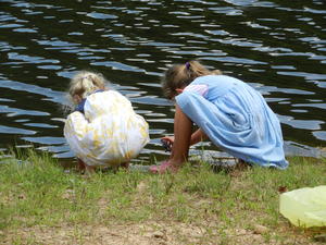 The girls playing near the pond.