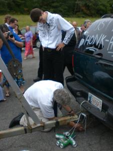 But the source was under the back of the car--an external horn wired to the blinker lights on the hitch! Here his Dad is unhooking it for him, at the Groom's request. :)