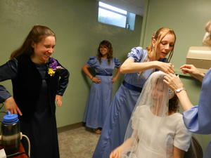 Kristina and Autumn putting on Kristina B's veil, while Kimberly observes.